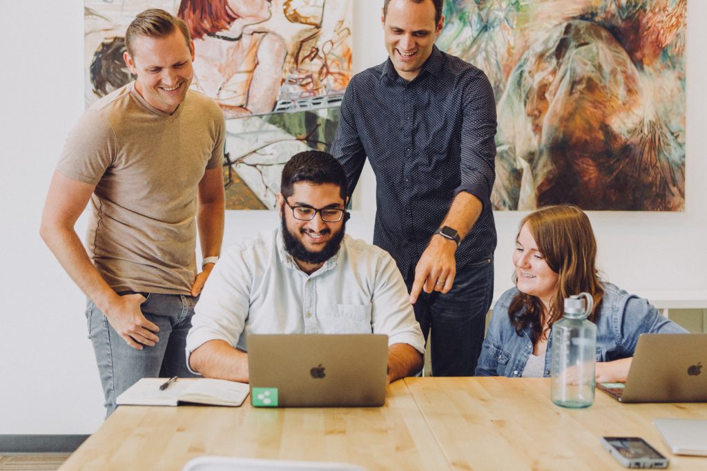 group of business dressed individuals working around a table looking at a computer